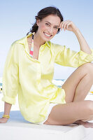 Brunette woman in yellow blouse and white shorts on the beach