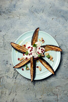 Baked eggplant served with yogurt and pomegranate seeds