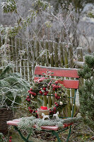 Wreath made of moss, ornamental apples, and mistletoe on a garden chair