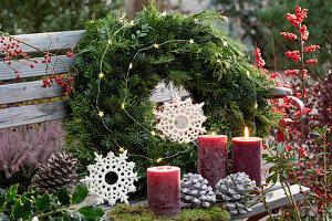 Wreath of mixed branches and candles on a garden bench