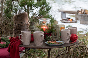 Becher, Windlicht und mit Fell umwickelte Thermosflasche auf Vintage Gartentisch