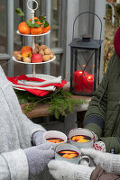 Hände mit Handschuhen stoßen mit Glühwein an