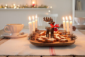 Christmas decoration with biscuits, reindeer figurine and candles on a wooden tray