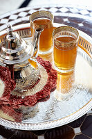 Teapot and two glasses of Asian tea on silver tray