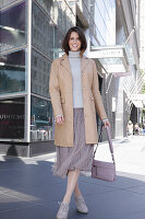 Brunette woman in turtleneck, skirt and beige leather coat