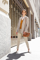 Brunette woman in mustard yellow sweater, light blazer and trousers