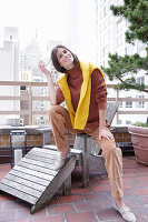 Brunette woman in autumn outfit with a yellow knitted sweater over her shoulders