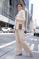 A brunette woman wearing a beige trouser suit walking down the street