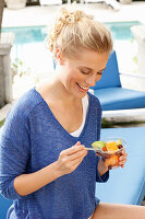 Blonde woman in blue shirt with dessert in hand