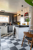 A black-and-white kitchen with a chequered linoleum floor
