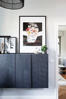 Floating chest of drawers with black wooden front and black and white photographs