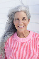 A grey-haired woman wearing a pink jumper