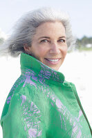 A grey-haired woman wearing a green coat