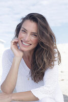 Happy long haired woman in white jumper on the beach