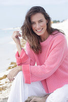 Long haired woman in pink jumper and white trousers