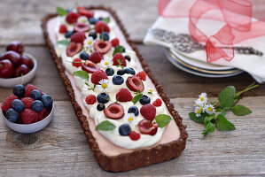 Berry tart with an oat-chocolate base and vegan cream cheese substitute cream