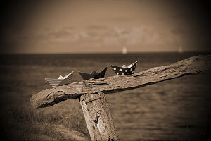 Paper boats on a wooden railing