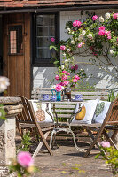 Vintage table with chairs on terrace with roses in bloom