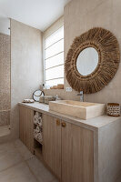 Tiled bathroom in beige tones, round mirror with raffia frame