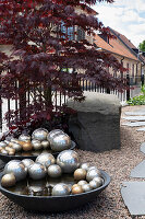 Schalen mit Silberkugeln, japanischer Ahorn und Granitblock am Gartenweg entlang
