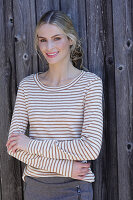 Young blonde woman in a striped shirt in front of a board wall