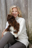 Mature blonde woman with dog in white knitted jumper and grey leggings