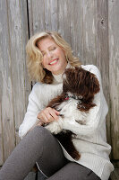 Mature blonde woman with dog in white knitted jumper and grey leggings