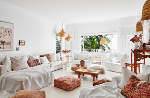 Weiße Sitzmöbel, marokkanische Kissen und Tische im Wohnzimmer
