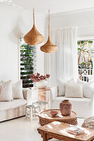 Weiße Sitzmöbel, marokkanische Kissen und Tische und Korblampen im Wohnzimmer