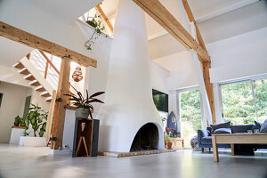 Kamin und Sofa in offenem Wohnraum mit weißen Wänden und Holzbalken