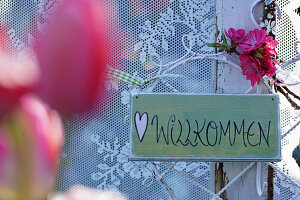 Welcome sign and bouquet of tulips as window decoration