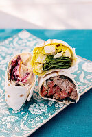Delicious tortilla wraps with assorted tasty filling with meat served on plate on table of outdoor cafe on summer day