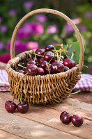 Cherries in a small basket on a wooden table