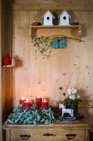 Advent wreath made of natural materials with red candles on a wooden chest of drawers