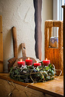 Adventskranz aus Naturmaterialien mit roten Kerzen auf einem Fensterbrett