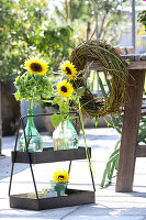 Sonnenblumen mit grünen Hortensien in Ballonflaschen und Kranz aus Weinranken