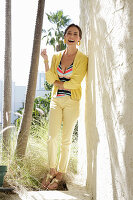 Junge brünette Frau in gestreiftem Tankinitop, gelber Hose und Jacke