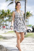 Brünette Frau in bedrucktem Sommerkleid am Strand