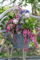 Bouquet of flowers in old watering can, watering heart (Dicentra Spectabilis) and columbine (Aquilegia) hanging on garden door