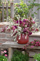 Blumenstrauß aus Brautspiere (Spiraea x arguta), Tulpen (Tulipa) und Zierapfel in Tonkrug im Garten