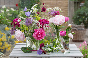 Summer flower arrangement in vases with peonies, ornamental leeks, bellflowers, goutweed and lady's mantle