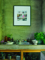 Kitchen utensils and herbs by a sink set in concrete