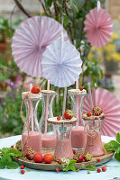 Strawberry shake in decorative bottles with wooden lids and straws
