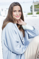 Young woman in light blue coat and light coloured trousers