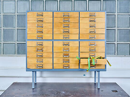 Cabinet in industrial design with wooden drawers and tape measure, glass block wall