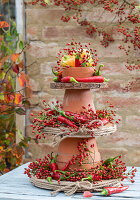 Homemade cake stand made of clay pots and wooden discs with rose hips