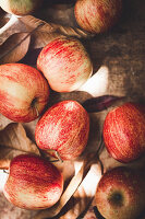 Red apples and autumn leaves on wooden background