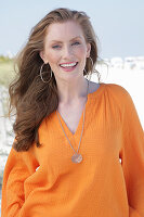 Young, blonde woman in an orange blouse on the beach