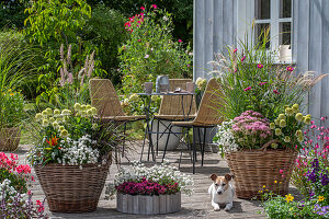 Tisch, Stühle und Sommerblumen in Pflanzkörben auf Holzterrasse