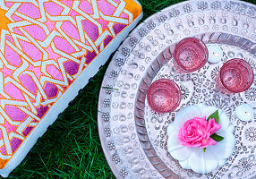 Pink glasses on silver tray on the grass